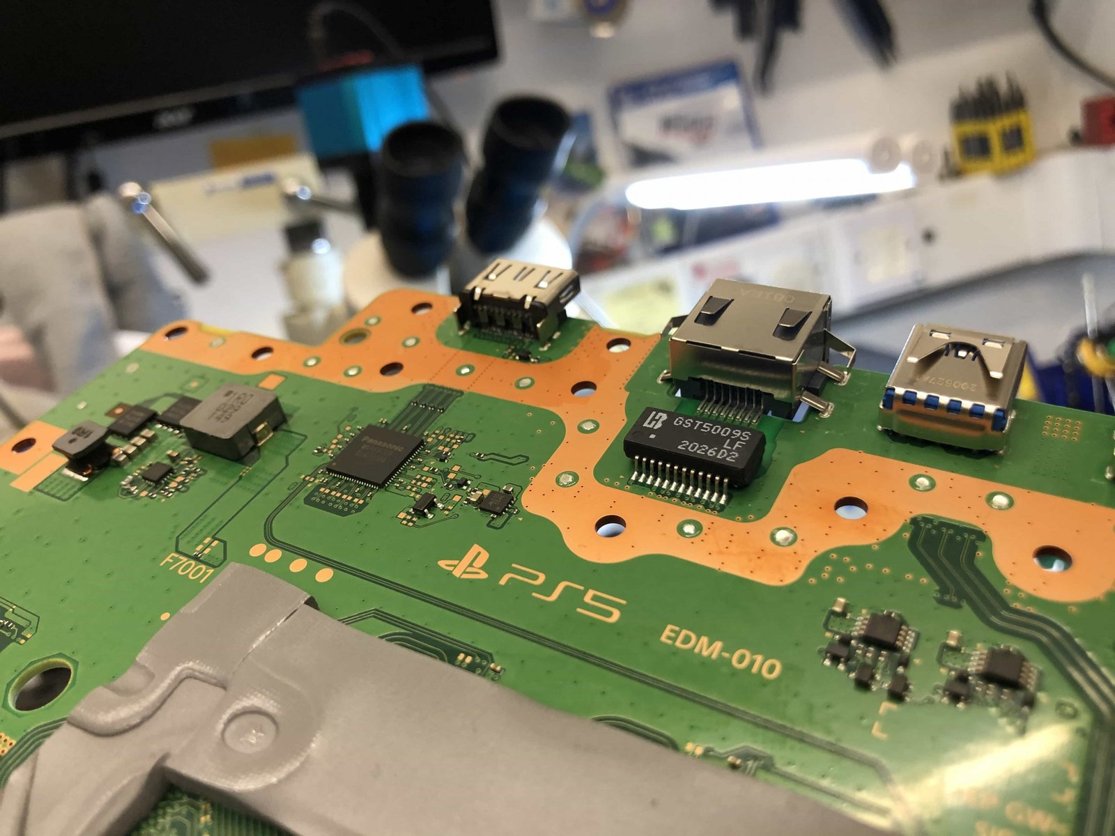 PS5 HDMI port repair Montreal — disassembled motherboard with HDMI port removed during micro-soldering process at BuyCellFix